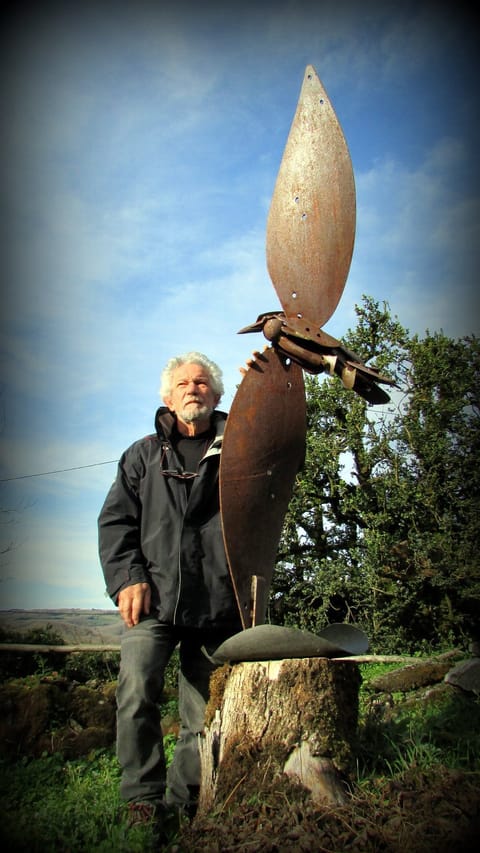 Robert Pujol devant l'une de ses sculptures, une hélice d'acier rouillé surmontée d'un oiseau