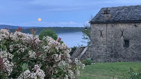 Pleine lune au-dessus de la brume, lilas en fleurs et maison de pierre